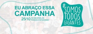 Logotipo do projeto Somos Todos Gigantes em verde e branco. Ao lado, a mensagem "Eu abraço essa campanha, 25 de outubro, Dia Nacional da Pessoa com Nanismo"
