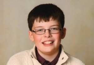 Foto de Benjamin, garoto de 10 anos; ele usa camisa vinho com um suéter branco de lã