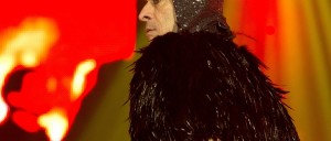 Foto artística de Ney Matogrosso com figurino coberto de penas negras, em um dos shows