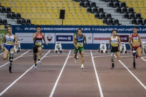 Cinco atletas paralímpicas vistas de frente disputam prova de velocidade.