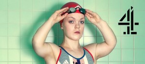 Nadadora com nanismo, em maiô esportivo, touca e óculos, olhando na direção da câmera