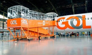 Foto de uma aeronave pousada em galpão, com uma rampa móvel acessível ao lado