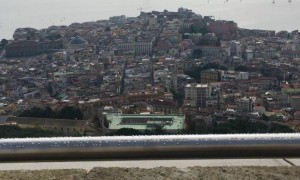 Foto em plano aberto da paisagem panorâmica da região da Campânia. No destaque, o corrimão com inscrições em braile