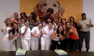 #PraCegoVer Foto de 17 pessoas, em uma sala da empresa Mars. Elas sorriem enquanto fazem um sinal em Libras com as mãos
