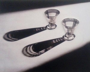 Foto de obra tátil que representa uma fotografia com dois copos em cima de uma mesa e suas sombras