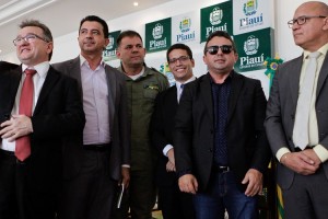 Foto de um com seis homens, posando para foto. Ao centro, há um cego com óculos escuros e bengala