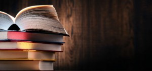 Foto de livros empilhados sobre uma textura que imita madeira