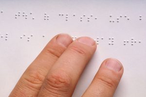 Dedos passando sobre folha em braille