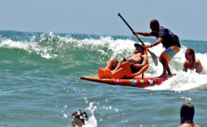 Foto de paratleta praticando surfe adaptado no mar.