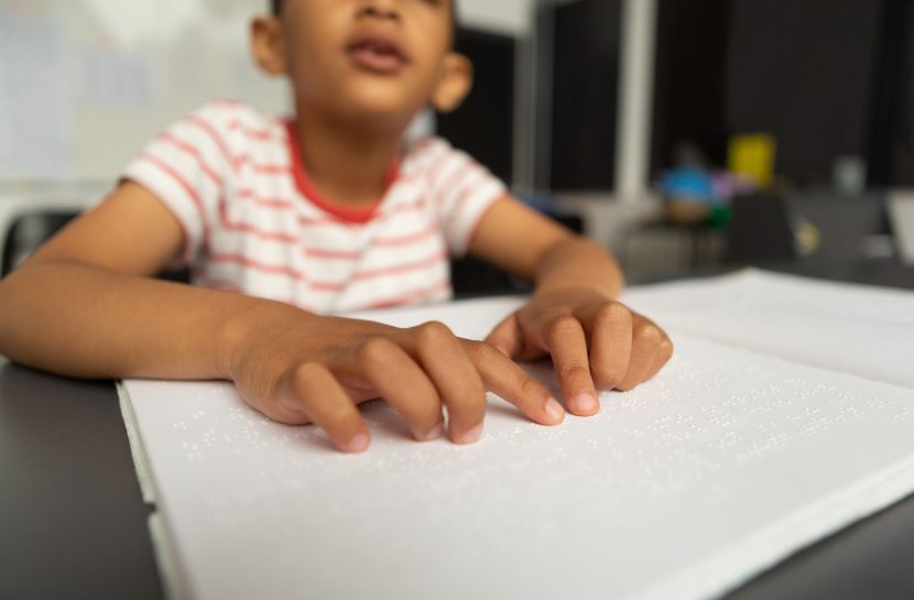 Criança cega lendo em Braille