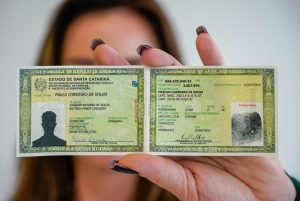 Mulher segura na altura do rosto documento de identidade brasileiro